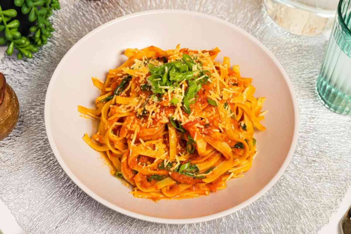 piatto di pasta con crema di carote e pomodori