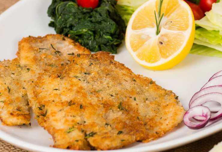 sogliola fritta in un piatto con verdure e limone