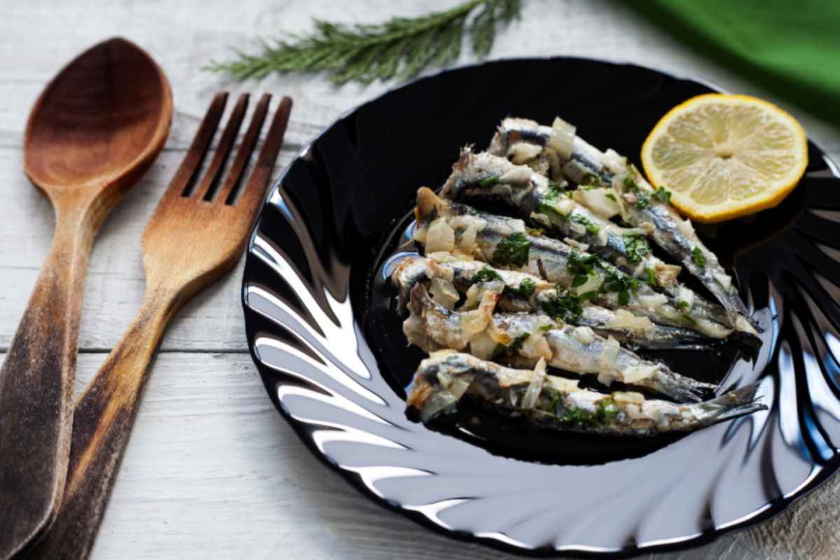 Alici con limone in un piatto nero
