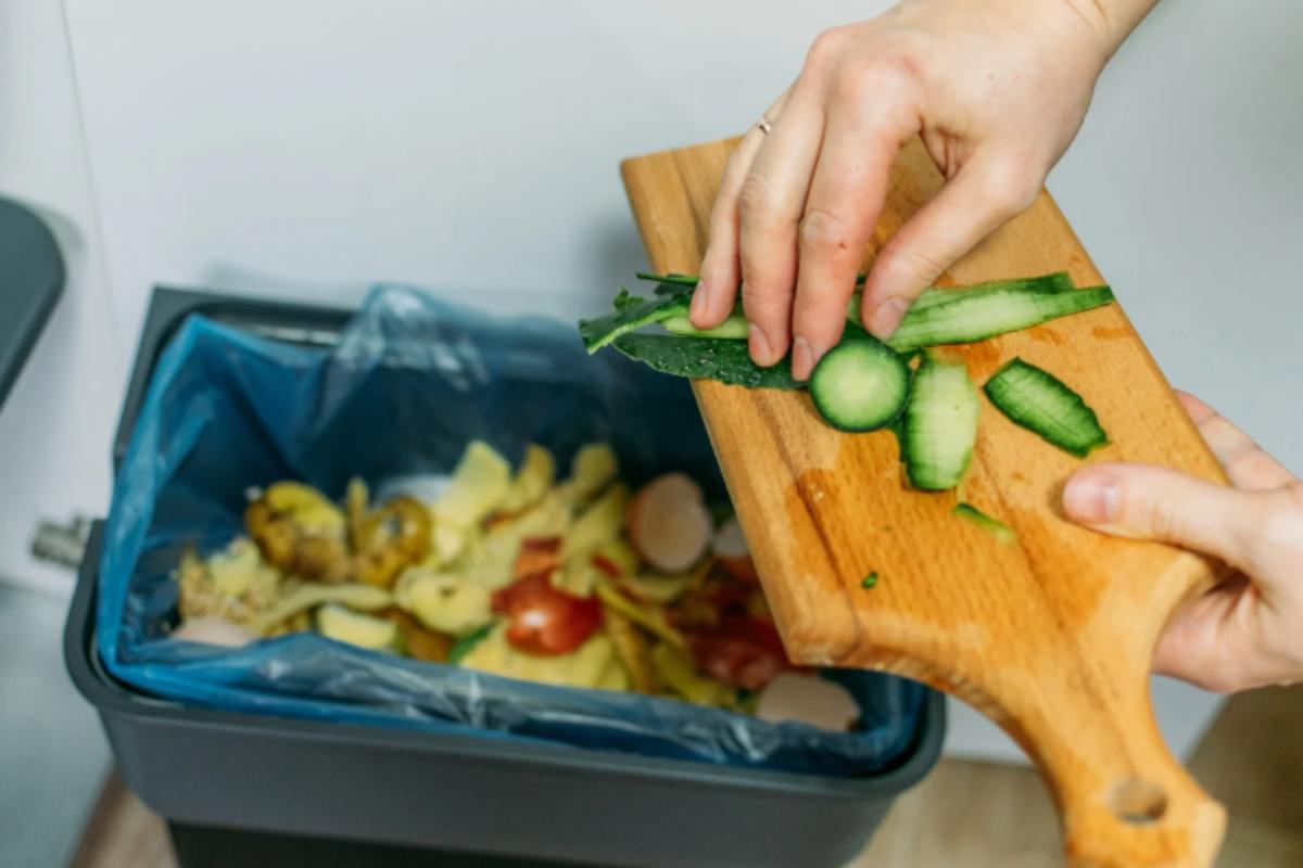 Donna che getta scarti di zucchine dell'umido