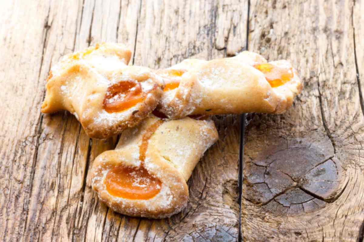 Biscotti ripieni di marmellata su legno