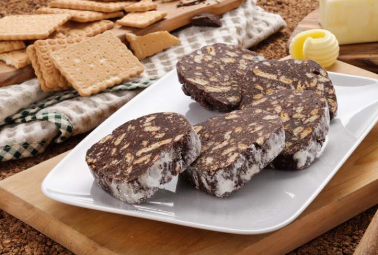 Salame di cioccolato a fette in un vassoio con biscotti