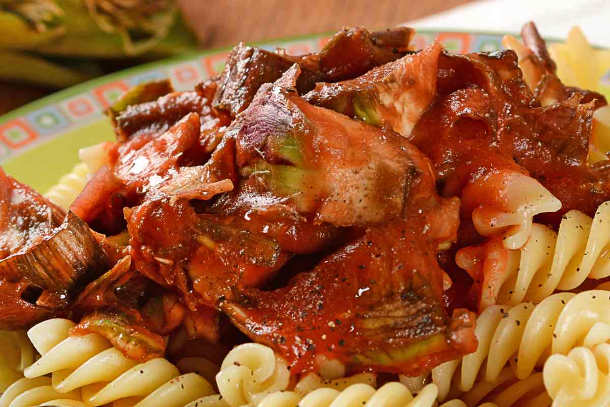 piatto di pasta con carciofi al pomodoro spolverati con pepe nero