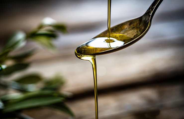 Un cucchiaio ricolmo di olio d'oliva che cola