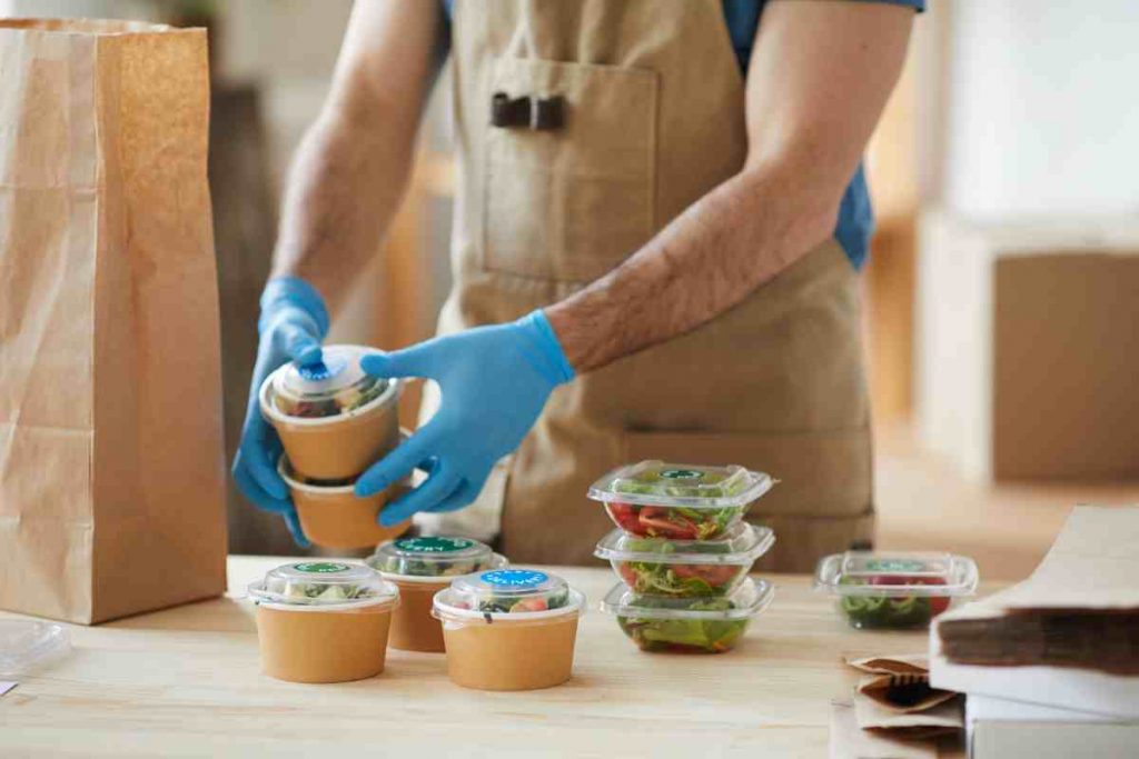 chef imbusta dei cibi da asporti preparati nella propria cucina
