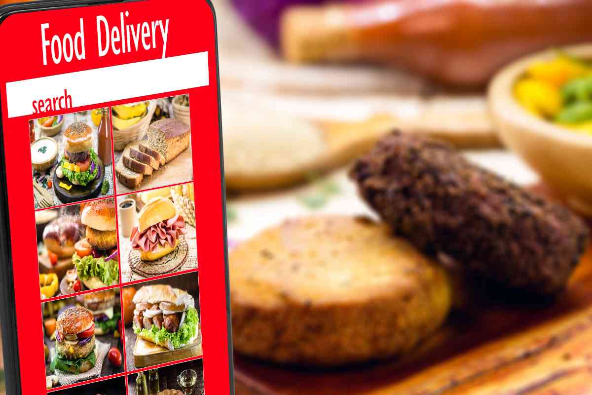 smartphone con app di food delivery e sullo sfondo vari cibi cucinati a casa