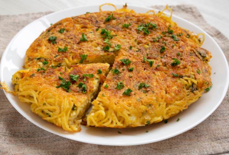 Frittata di spaghetti in un piatto con prezzemolo tritato in superficie