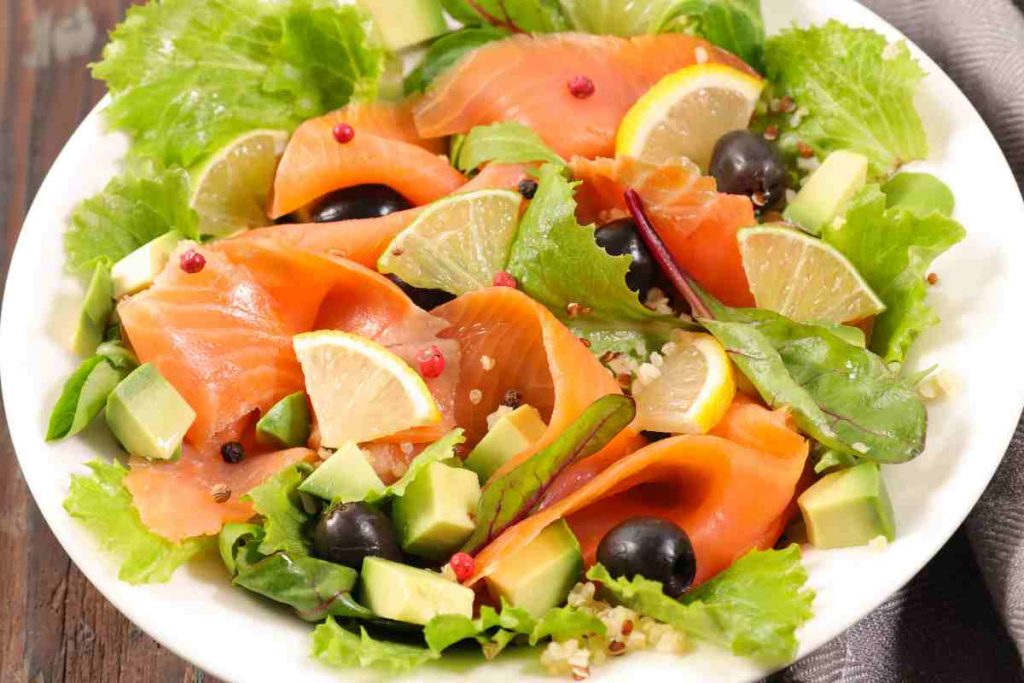 Insalata di avocado e salmone affumicato con olive e fettine di limone in un piatto
