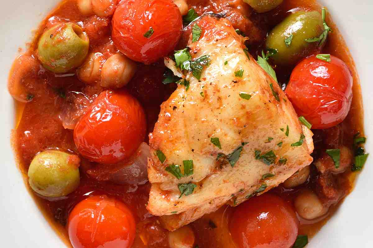 piatto di merluzzo in umido con pomodorini e olive visto dall'alto