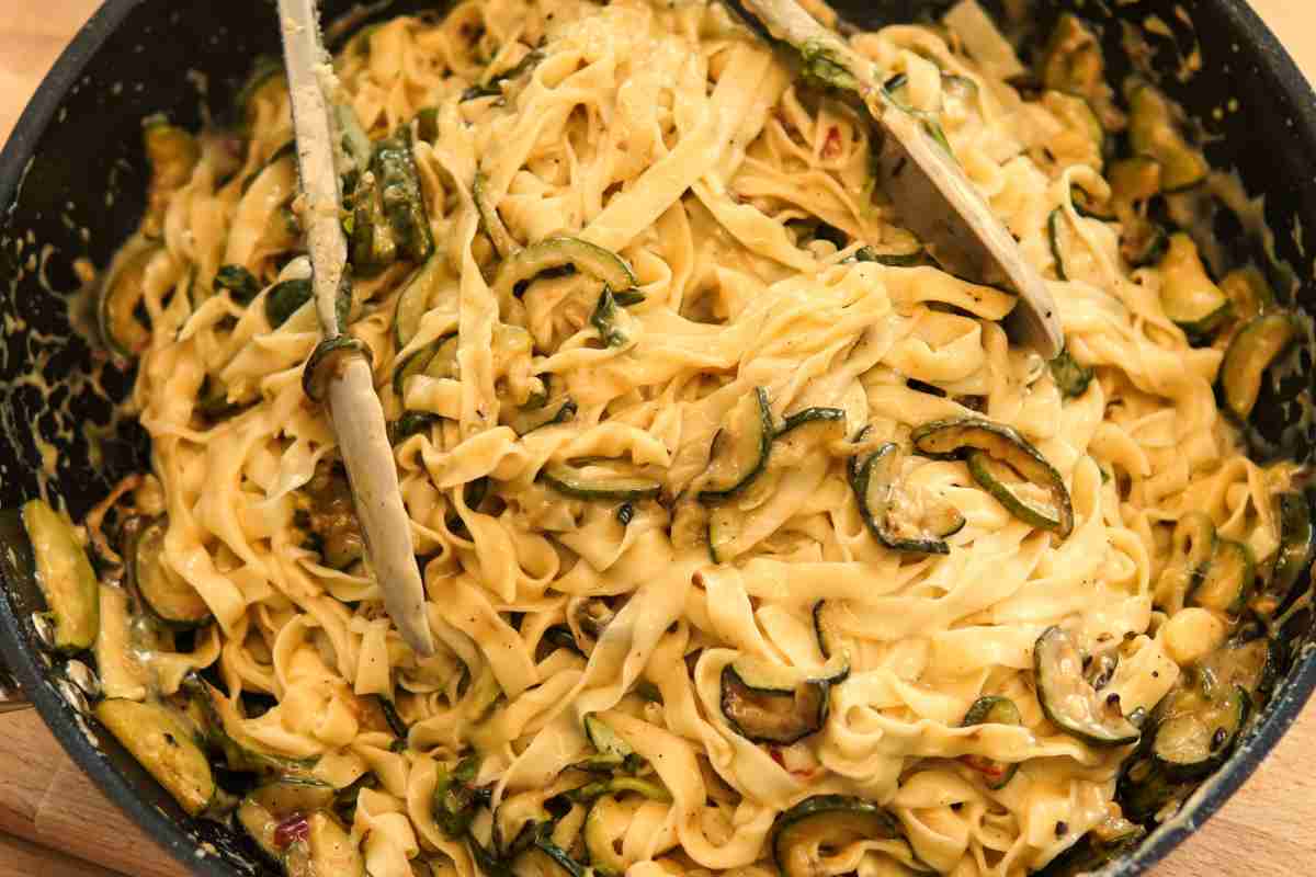 Pasta con zucchine robiola e speck in una padella