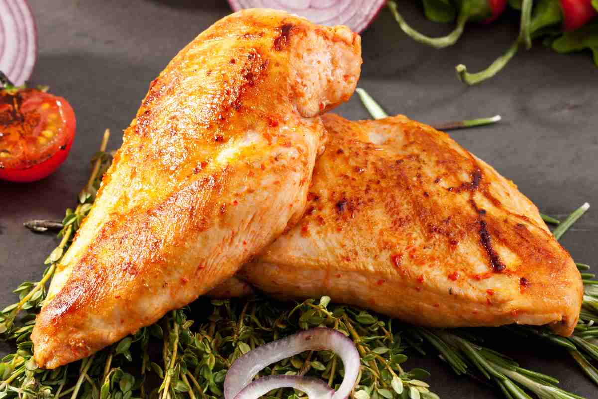 Due pezzi di petto di pollo al forno su un tagliere