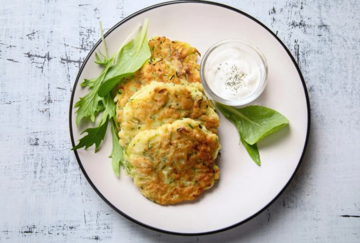 Frittelle di zucchine in un piatto con salsa