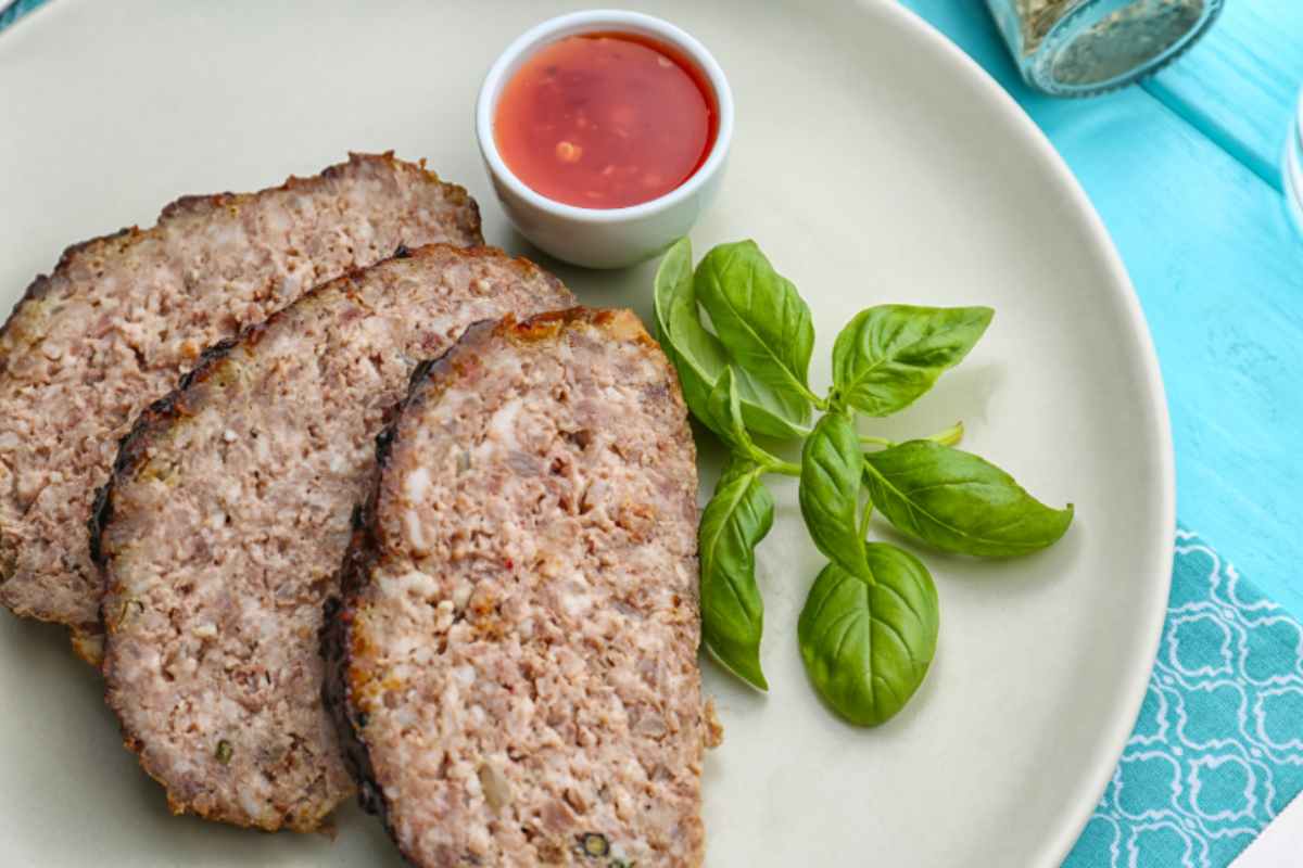 Fette di polpettone con foglie di basilico e salsa
