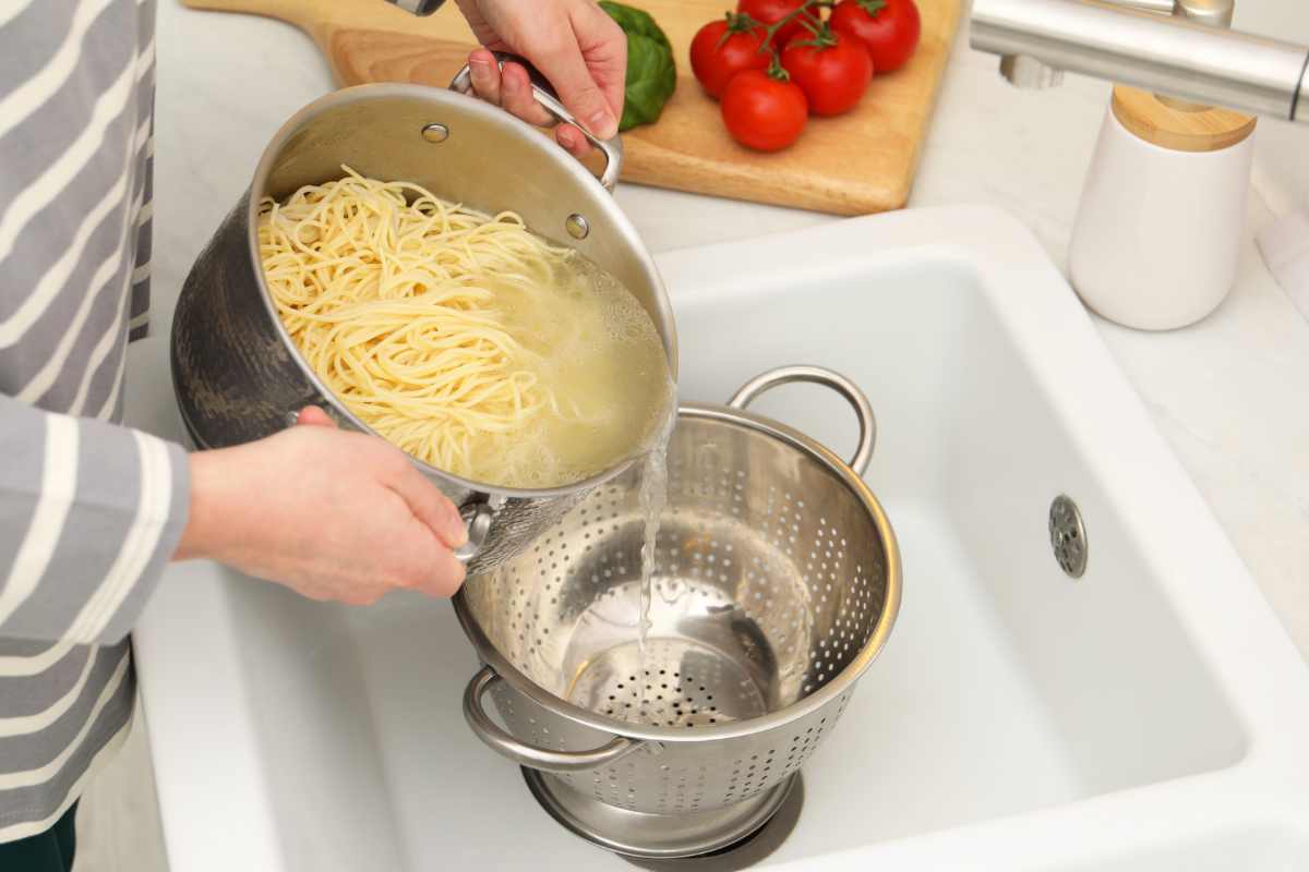Persona che scola l'acqua di cottura della pasta