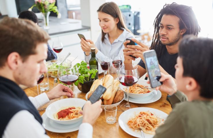 Persone a tavola che consultano lo smartphone