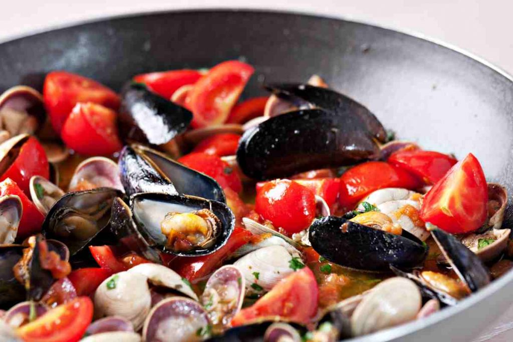 Sugo vongole e cozze con pomodorini in una padella