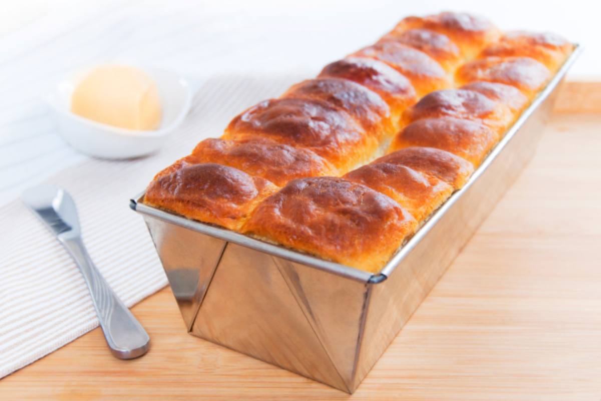 Plumcake in ruoto d'acciaio con coltello e panino accanto