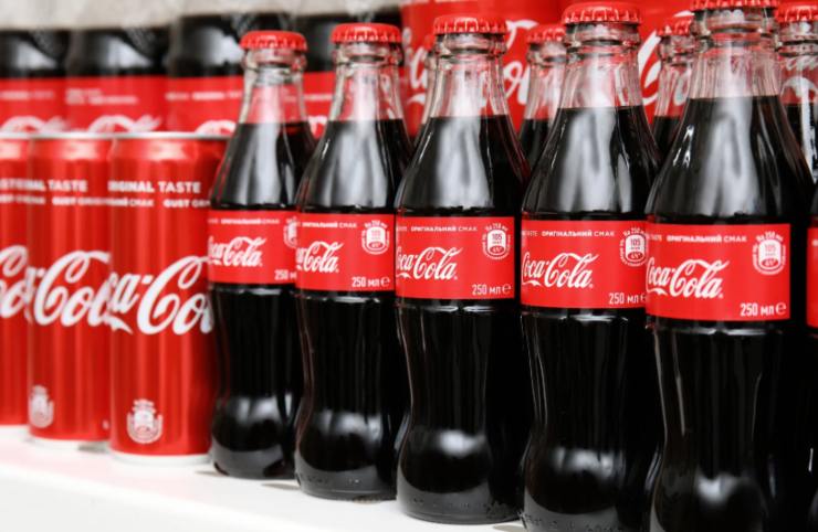 lattine e bottigliette di coca cola sullo scaffale del supermercato