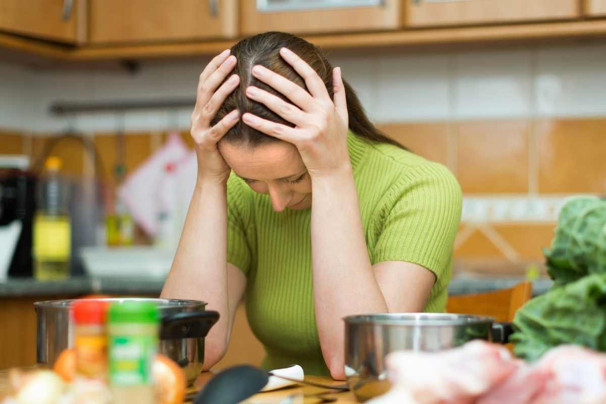 donna con le mani in testa in cucina