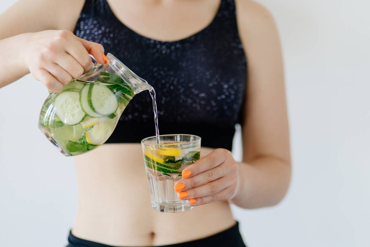 versare acqua con cetriolo e limone nel bicchiere