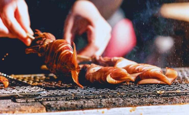 mani cuociono calamari sulla griglia