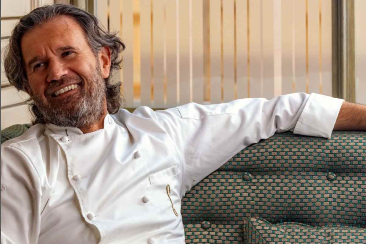 carlo cracco seduto su un divano che ride