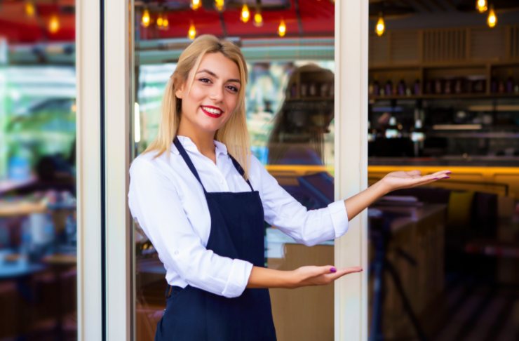 cameriera fuori dal ristorante che invita i clienti ad entrare