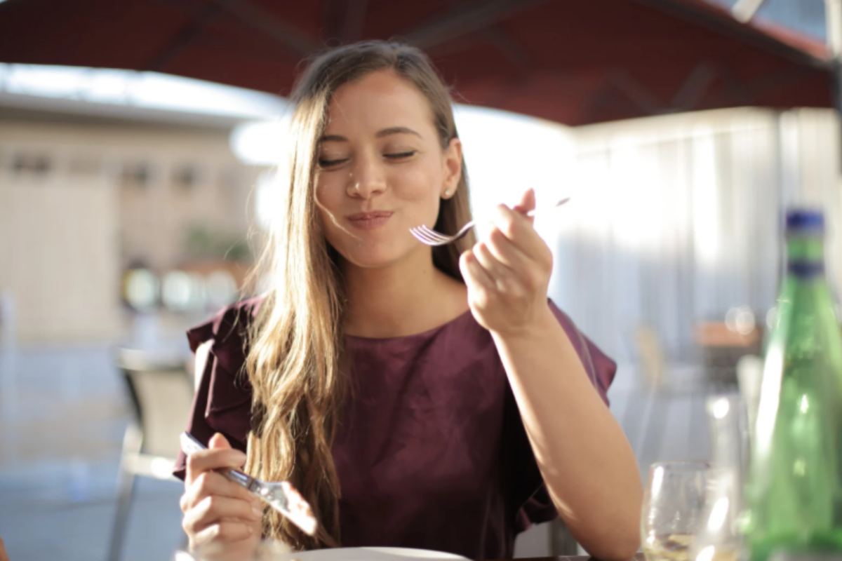 donna che mangia con gli occhi chiusi e l'espressione felice