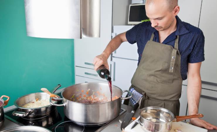 uomo che cucina con il vino