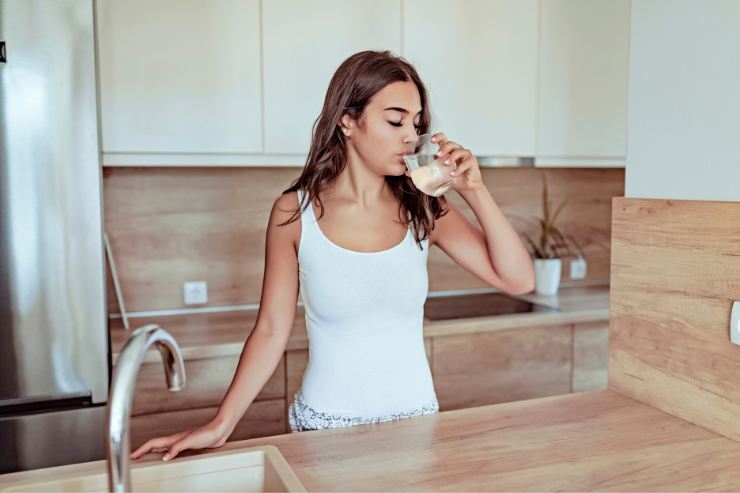 ragazza che beve un bicchiere di acqua