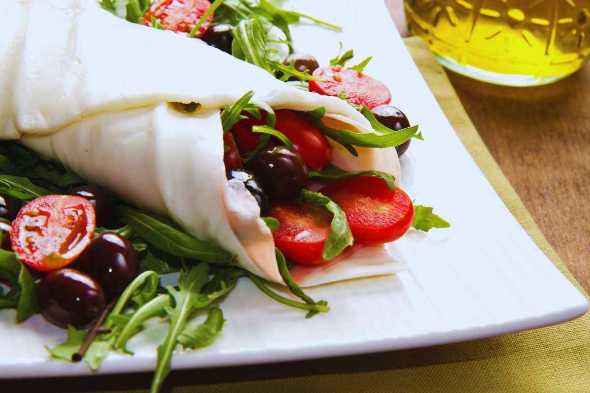 un rotolo di mozzarella con dentro rucola e pomodori