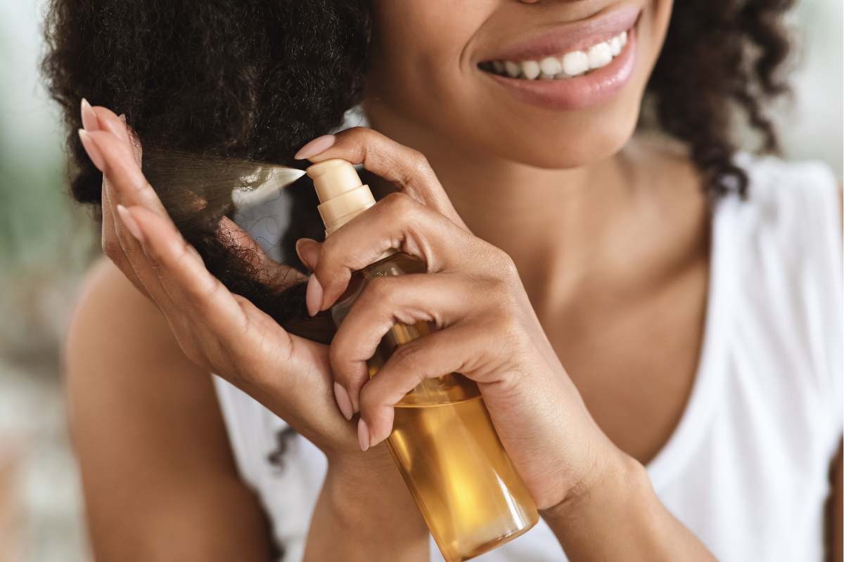 ragazza che spruzza olio sui capelli