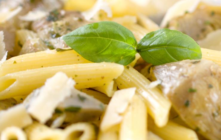 primo piano di penne condite con carciofi e parmigiano