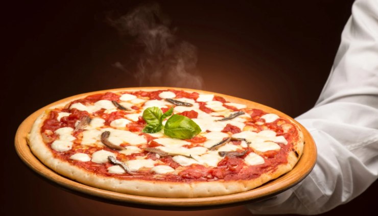 cameriere che porta una pizza fumante su un tagliere 