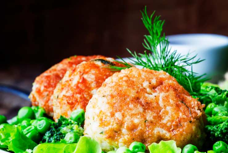polpette dorate in un piatto con piselli e erbe aromatiche