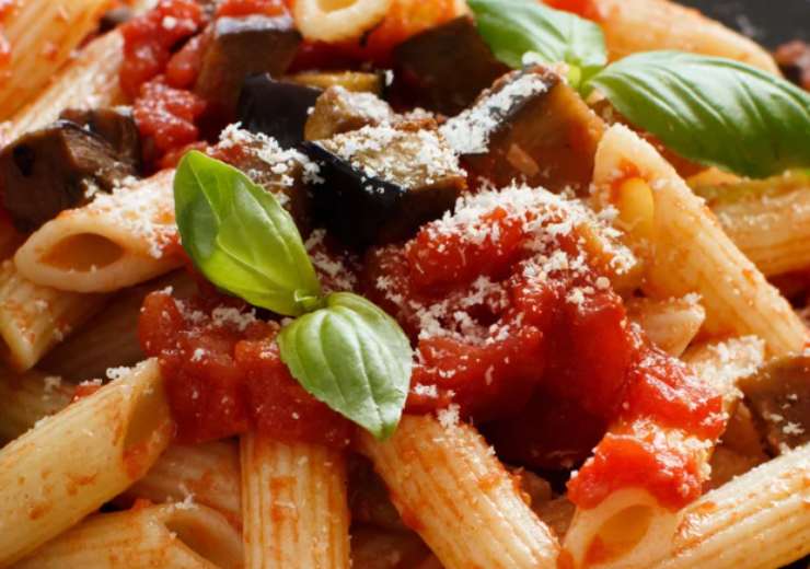 primo piano di maccheroni conditi con pomodoro e melanzane