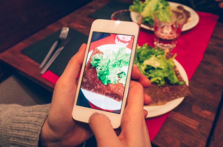 persona al ristorante che con il cellulare fotografa un piatto