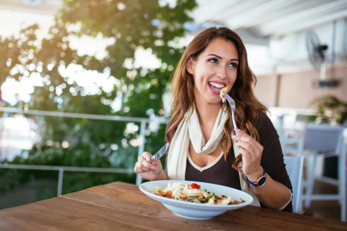 donna che mangia al ristorante e sorride