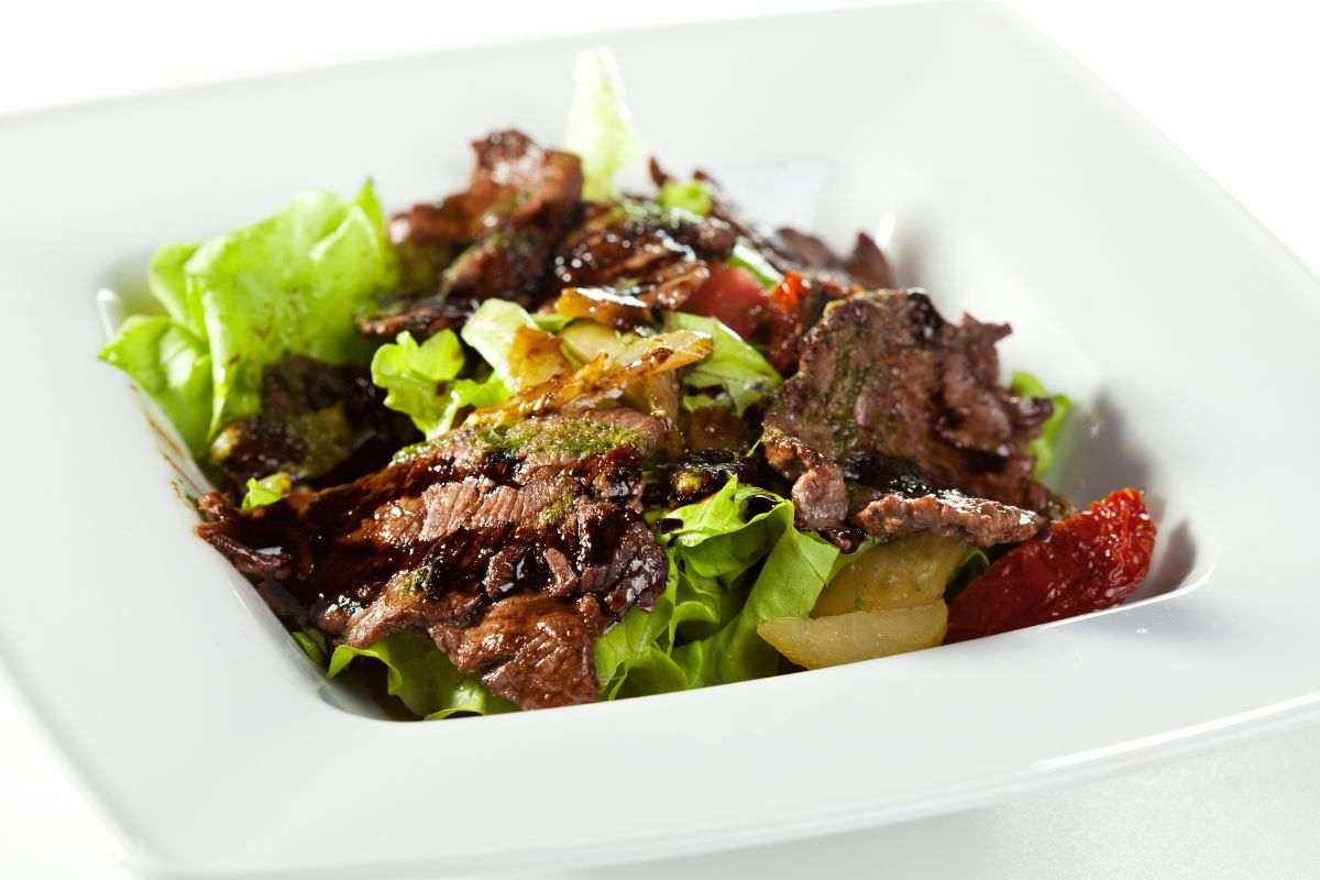 insalta di carne con aceto balsamico e pomodorini in piatto quadrato