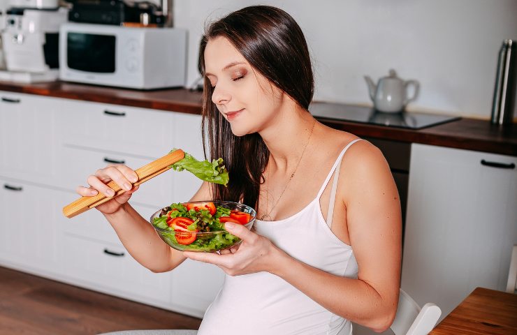 Una donna incinta che mangia ortaggi