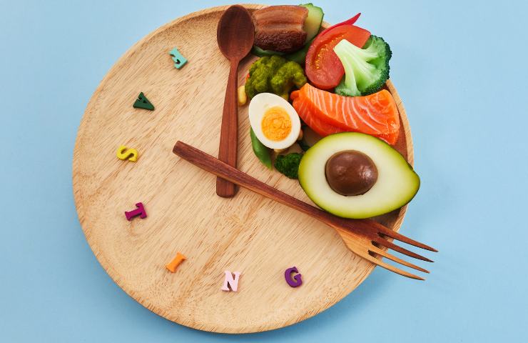 Alimenti in un piatto con posate a formare un orologio