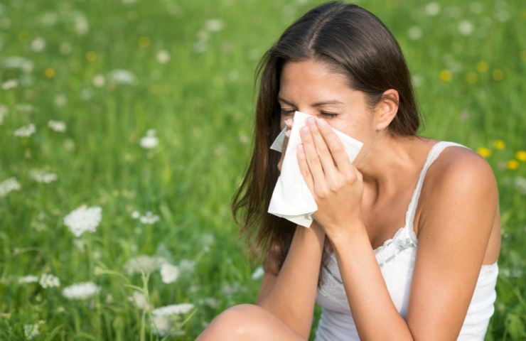 Una ragazza preda dell'allergia su di un prato