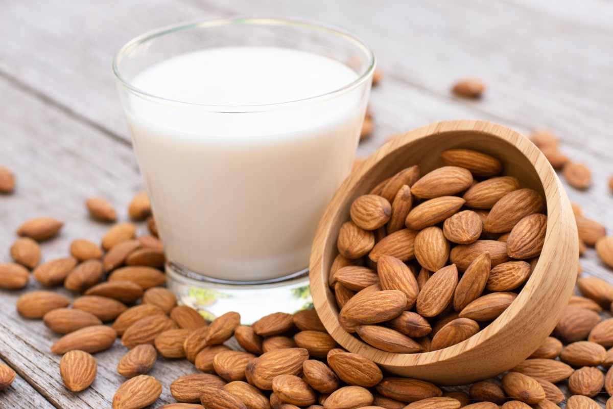un bicchiere di latte di mandorla e mandorle intorno