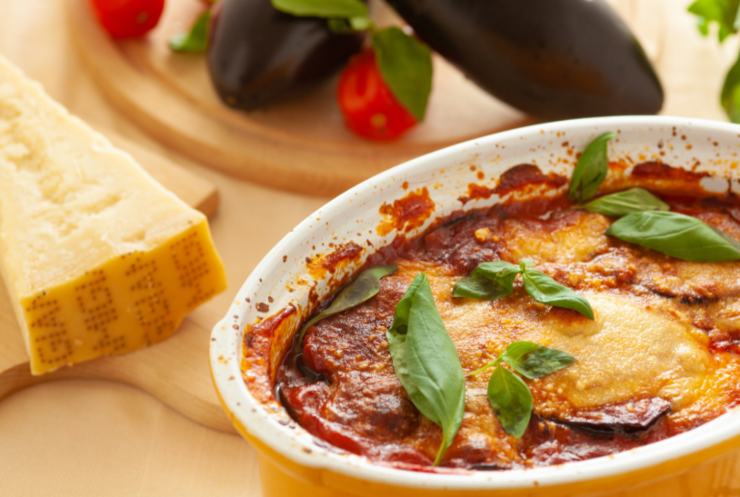 Parmigiana di melanzane con parmigiano accanto