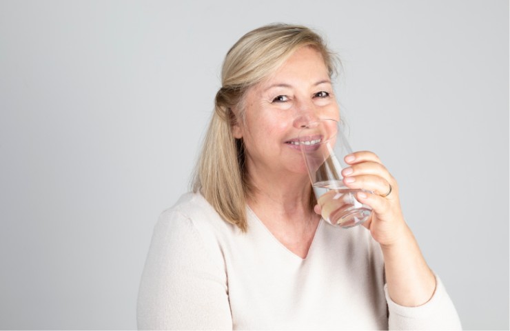 Una donna di mezza età che beve acqua