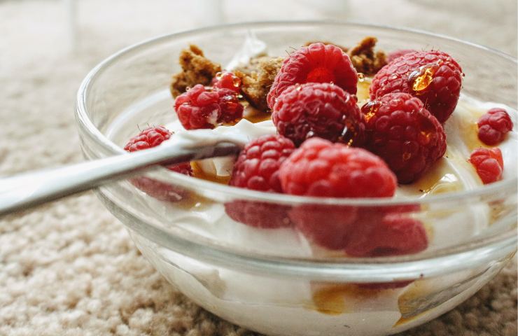 Una ciotola riempita con yogurt greco, muesli e lamponi