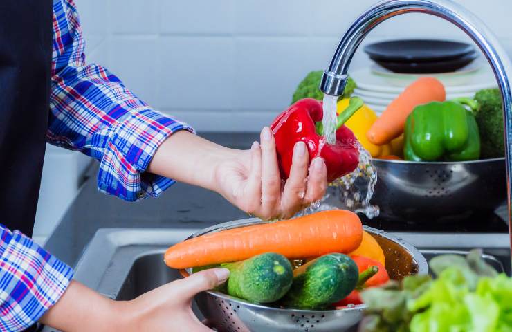 Una persona che sciacqua delle verdure fresche