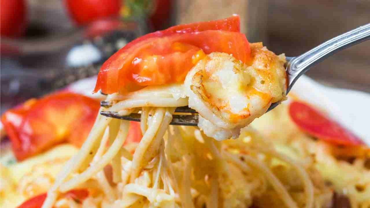 Un piatto di spaghetti con gamberi, pomodori e mozzarella