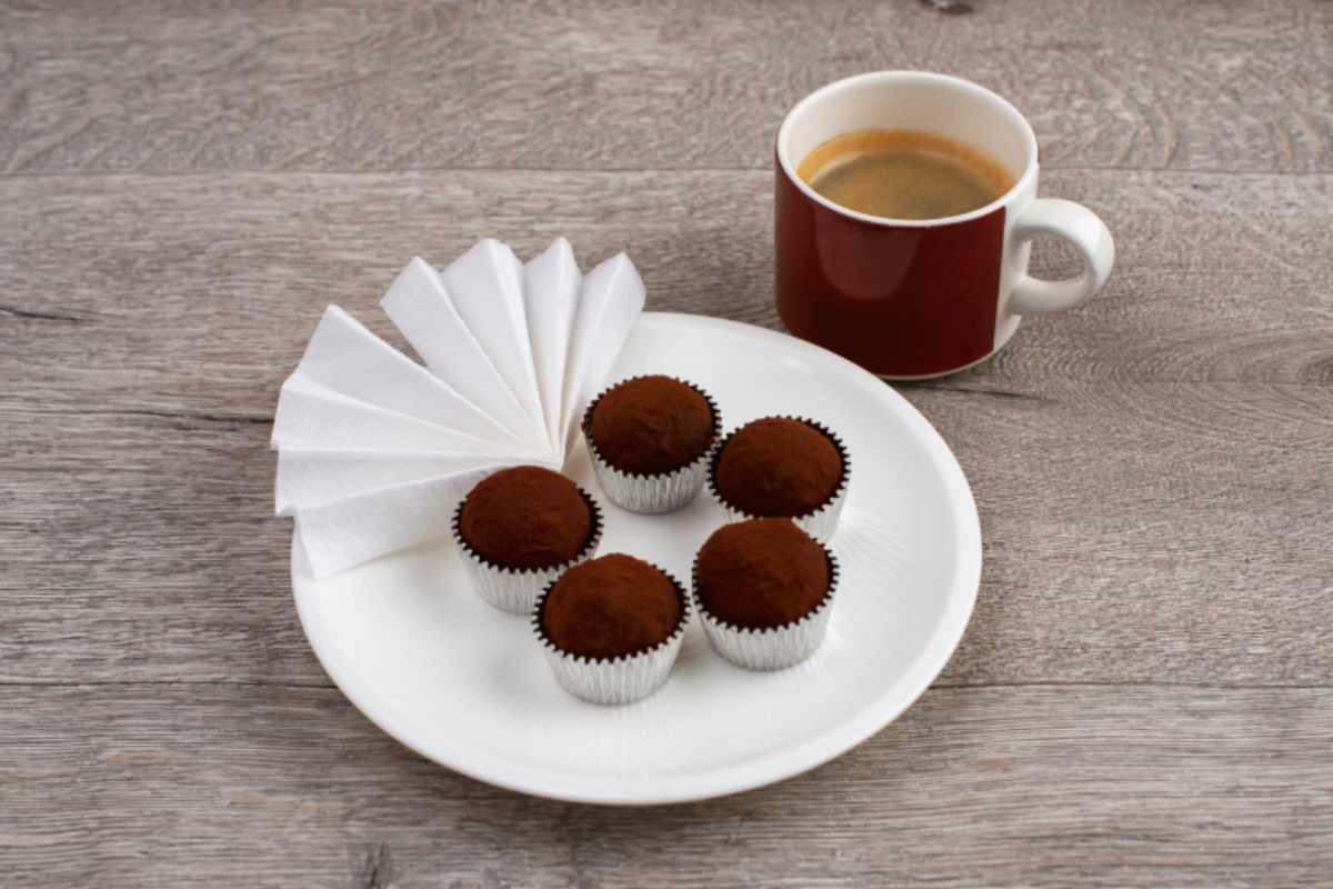 Tartufini al cacao in un piatto con una tazza di caffè accanto