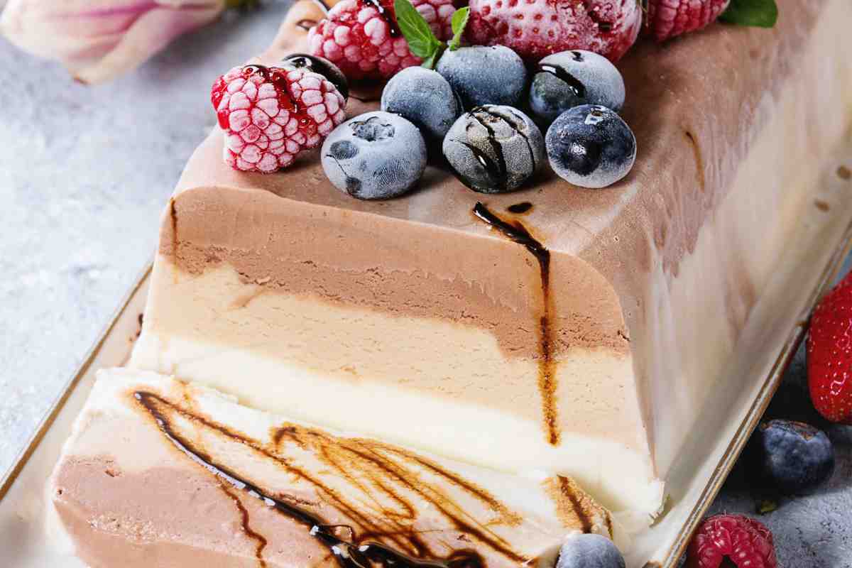 Torta gelato a strati vaniglia nocciola e cioccolato decorata con frutta fresca